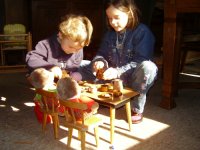 two children at a set table with dolls